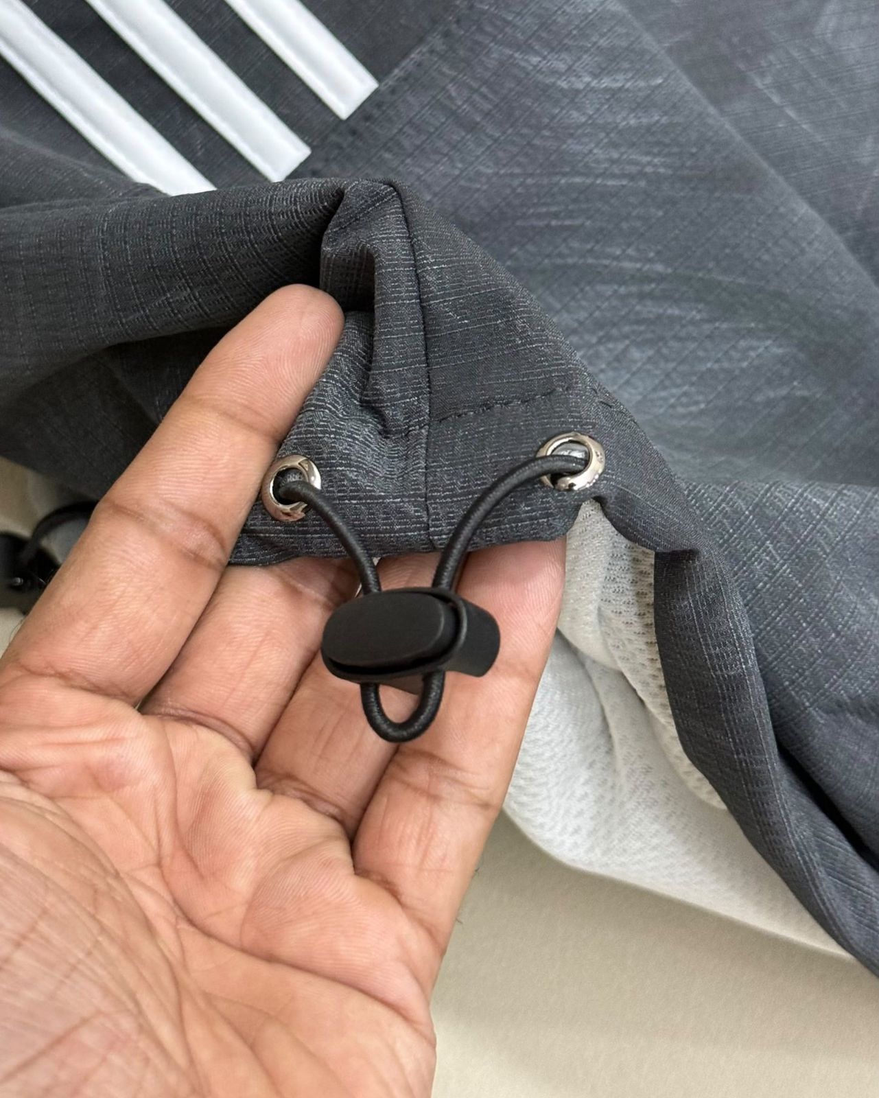 Hand holding the bungee drawcord and toggle at the windbreaker hem