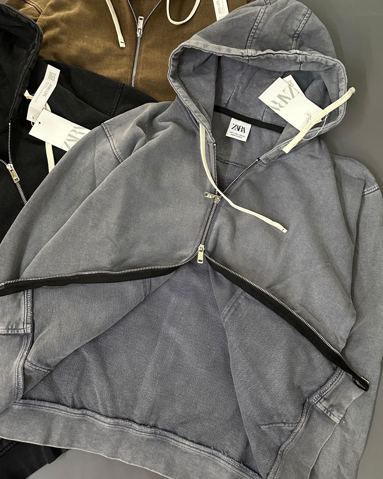 Slate grey hoodie unzipped from the bottom showing the two-way zip and twill inside