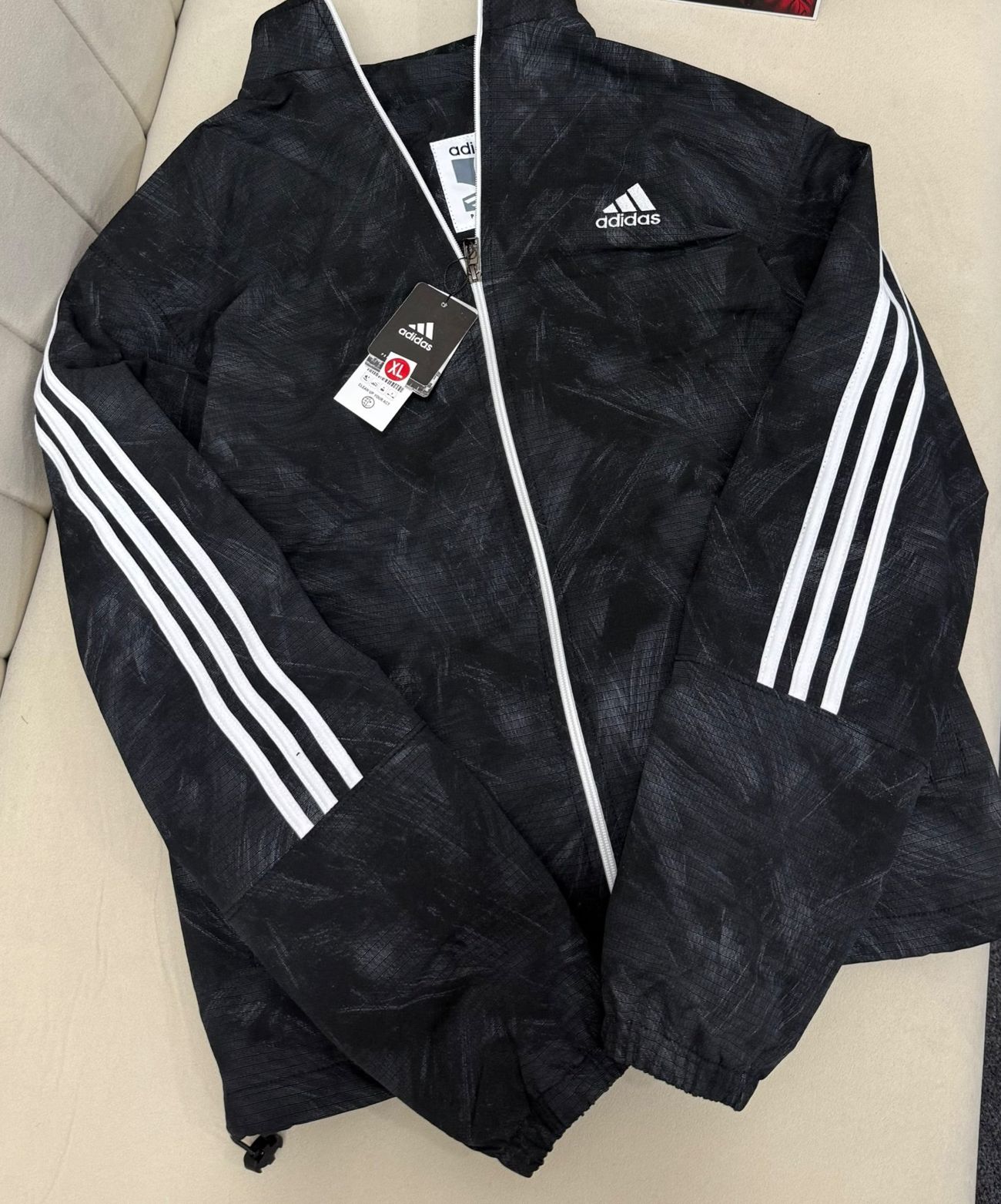Black track windbreaker with three white sleeve stripes